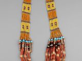 un gros plan d'un collier orné de plumes et de perles