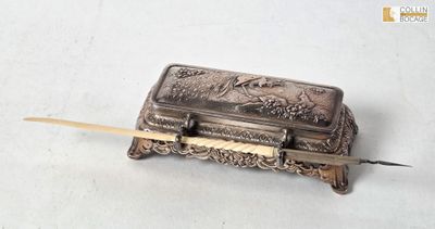 une vieille boîte en argent munie d'une poignée en bois, posée sur une surface blanche