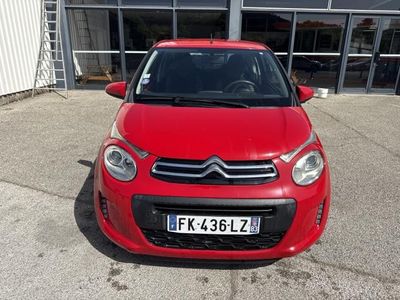 La petite voiture rouge est garée devant un immeuble.