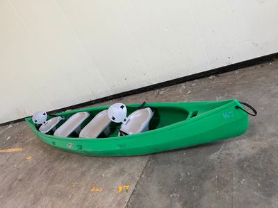 un kayak vert avec quatre pagaies posées par terre