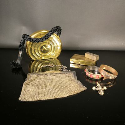 un sac à main doré et d'autres objets posés sur une table noire