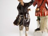 two figurines of men dressed in period clothing standing next to each other