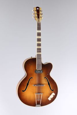 a brown guitar sitting on top of a white surface