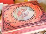 une boîte rouge ornée d'une image, posée sur une pile de livres