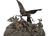 sculpture en bronze représentant un oiseau posé sur un rocher, entouré de fleurs et d'oiseaux