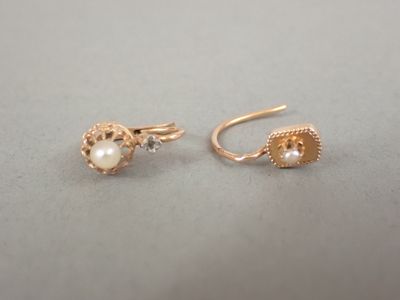 une paire de boucles d'oreilles en or ornées de perles, posée sur une table
