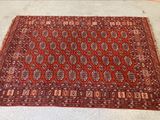 Le tapis posé au sol est rouge et marron, avec un motif.