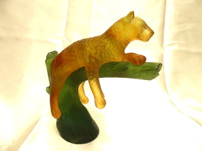 une figurine représentant un ours assis sur une branche d'arbre