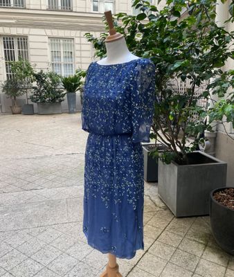 the dress is on a mannequin stand in front of a potted plant