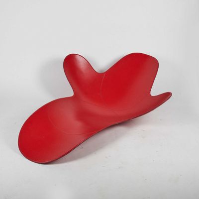 un objet rouge posé sur une surface blanche, avec un fond blanc