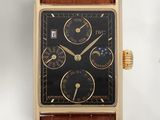 une photo d'une montre en or avec un cadran noir, montée sur un bracelet en cuir marron
