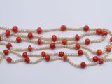 a close up of a red and white beaded necklace on a white surface