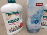 three bottles of saniti and a bottle of deodorance on a counter
