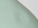 a green glass bottle with a small amount of water on it