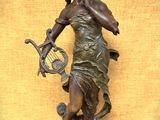 statue en bronze représentant une femme tenant une harpe, posée sur un socle en bois