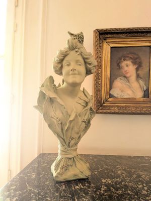 une statue représentant une femme assise sur une table, à côté d'un tableau