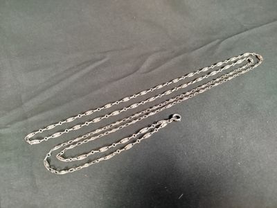 deux chaînes en argent sont posées sur un tissu noir