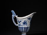 a blue and white porcelain pitcher with a handle on a black background