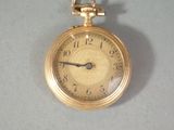 a gold pocket watch on a table with a white background