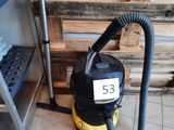 un aspirateur posé par terre à côté d'une étagère