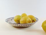 a bowl of lemons next to a bowl of lemons on a table