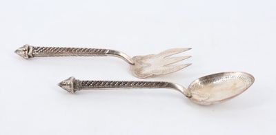 deux cuillères et une fourchette en argent sur une surface blanche