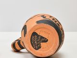 two orange and black vases sitting on a table