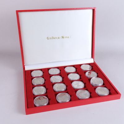 une boîte rouge contenant douze pièces d'argent, posée sur une surface blanche