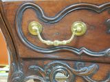 a wooden chest of drawers that has a brass handle on it
