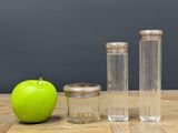 three glass jars and a green apple on a table