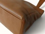 brown leather handbag on a white background with a blue label