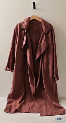 Une photo d'un manteau est accrochée à un cintre sur un mur.