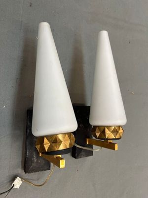 une paire de lampes blanches et dorées en forme de cône, fixées à un mur gris