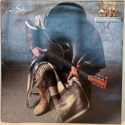 une vieille photo d'un homme assis par terre avec une guitare