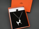 une boîte orange contenant un pendentif en forme de chien argenté