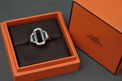 une boîte orange contenant un anneau argenté, posée sur une surface noire