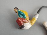 a figurine of a man sitting on top of a pipe