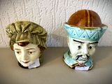 deux vases ornés de visages, posés sur une table