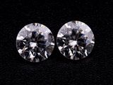a pair of round brilliant cut diamonds on a black background