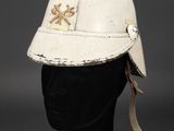 an old white helmet on a mannequin head on a black surface