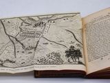 un livre ouvert, sur lequel figure une carte, posé sur une table