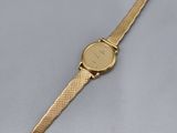 gros plan d'une montre en or sur une surface blanche