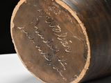 a brown vase with writing on it sitting on a table
