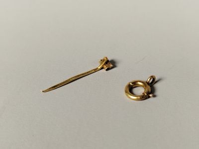une paire de boucles d'oreilles en or et une bague en or posées sur une surface blanche