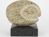 une sculpture en pierre représentant un escargot, posée sur un socle en marbre noir
