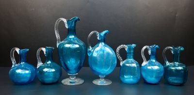 Plusieurs vases en verre bleu sont alignés sur une table