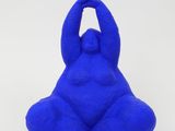 a close up of a blue sculpture of a person sitting on a white surface