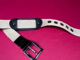 a close up of a white belt with a black buckle on a pink background