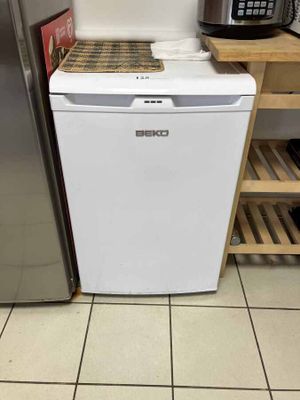 a small white refrigerator in a kitchen with a coffee maker on top of it