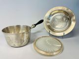 silver plate with a spoon and a bowl on a white surface